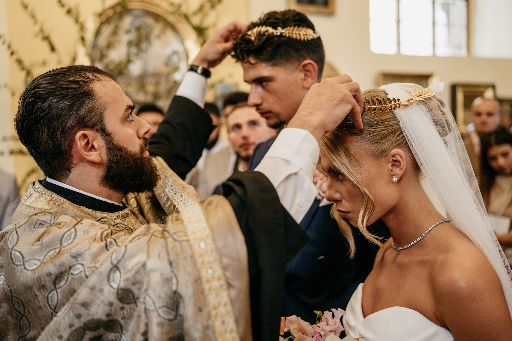 Pop nakłada złote wieńce korony na głowę pary młodej - ceremonia zaślubin w obrządku grekokatolickim